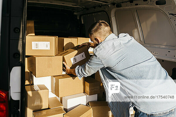 Young delivery man arranging packages in van