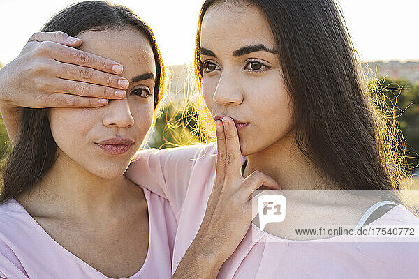 Sisters covering each other's eye and mouth