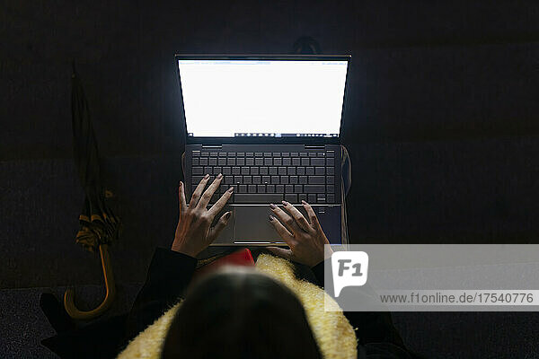 Teenager typing on laptop at night