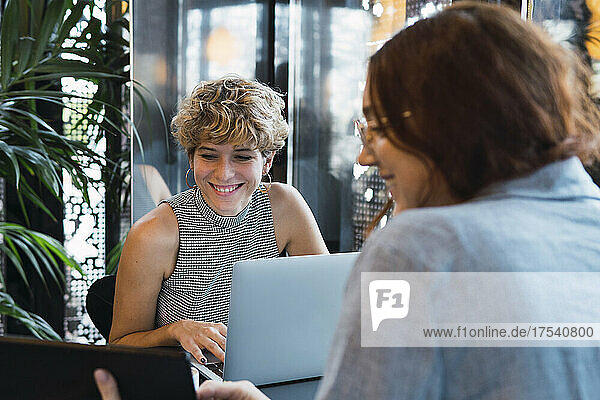 Smiling business colleagues discussing on table at coffee shop