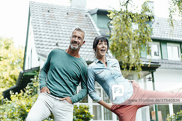 Cheerful couple with hands in pockets at backyard