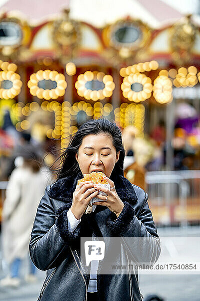 Woman eating burger at amusement park