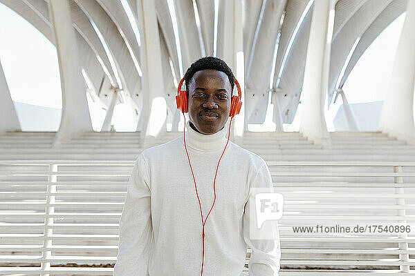 Smiling young man wearing orange colored headphones