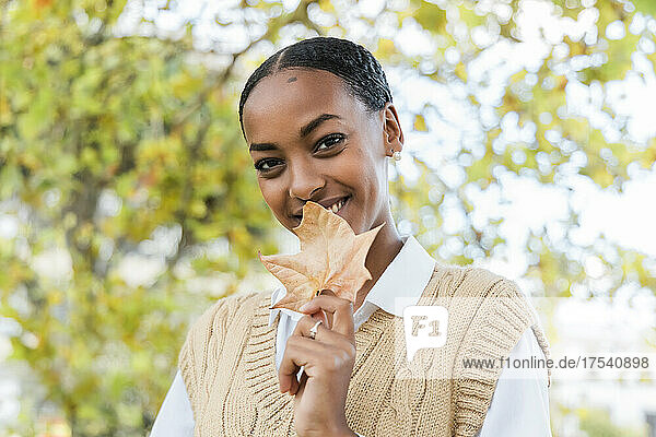 Beautiful girl holding autumn leaf