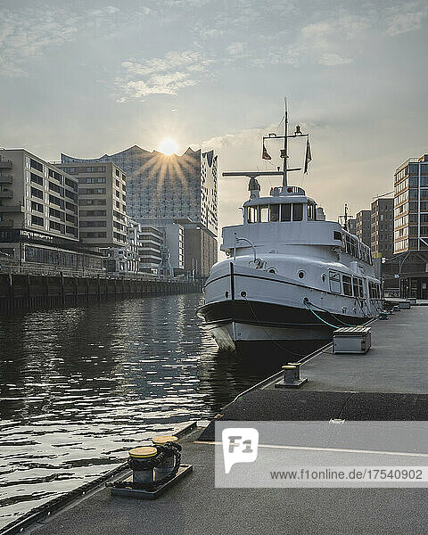 Germany  Hamburg  Boat moored in Sandtorhafen canal with sun setting over Elbphilharmonie in background