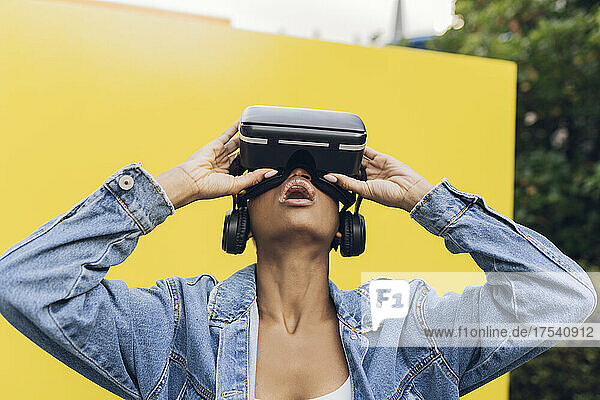 Woman wearing virtual reality headset in front of yellow wall