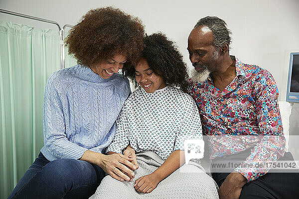 Happy family sitting together on bed at hospital