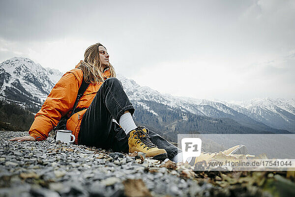 Hiker with coffee mug contemplating on mountain in winter
