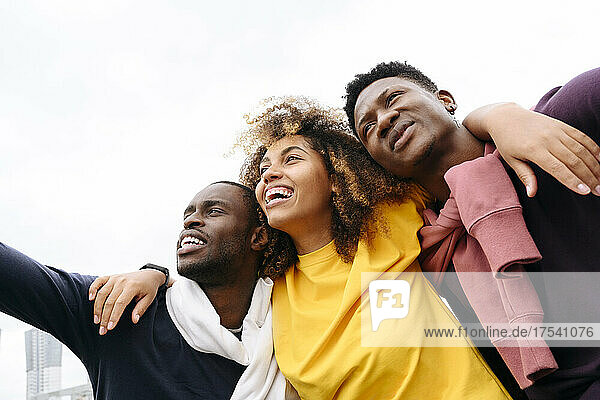 Cheerful multiracial friends in front of clear sky