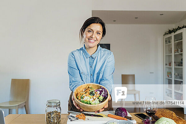 Smiling woman holding salad bowl at home
