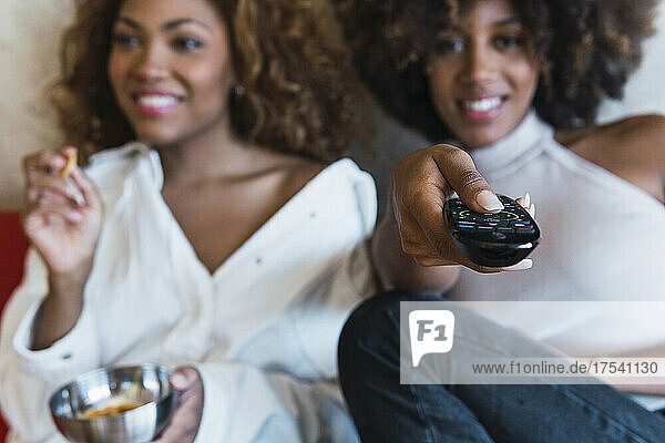 Woman using remote control with friend at home