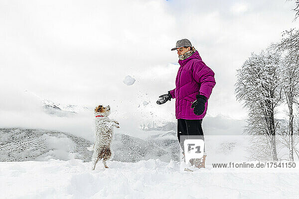 Man and dog playing with snow