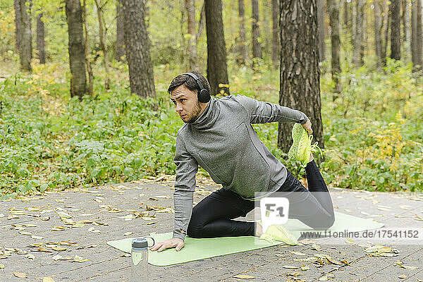 Sportsman with wireless headphones exercising at park