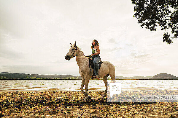 Young woman riding horse at waterfront