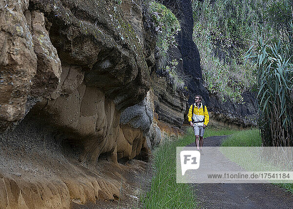 Hiker with backpack walking on road by rock formation