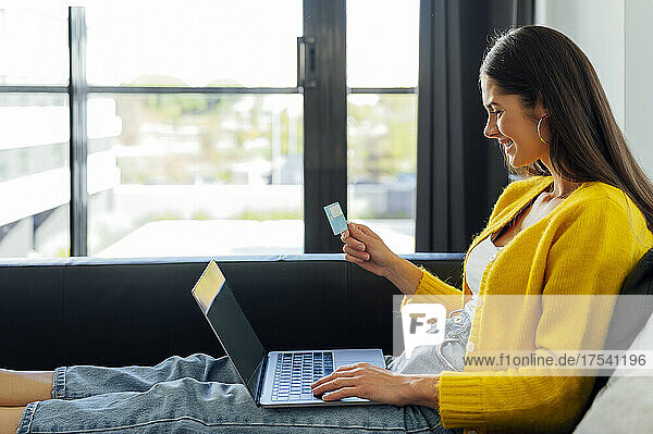 Happy woman with credit card doing online shopping in living room