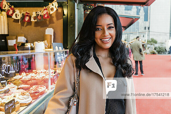 Happy woman standing near doughnut shop in market