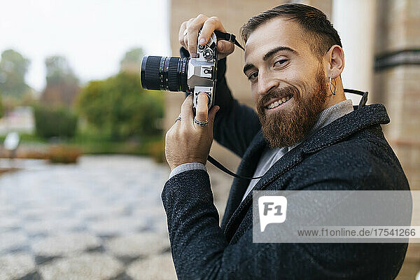 Smiling young bearded man with camera