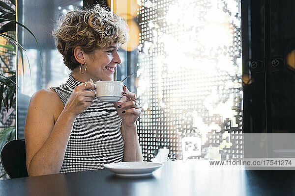 Lächelnde junge Frau mit Kaffeetasse im Café