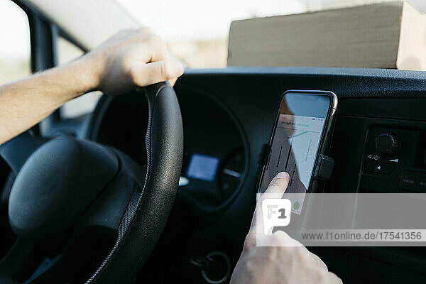 Man using GPS on smart phone while driving van