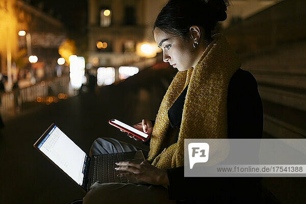 Teenage girl using laptop and smart phone at night