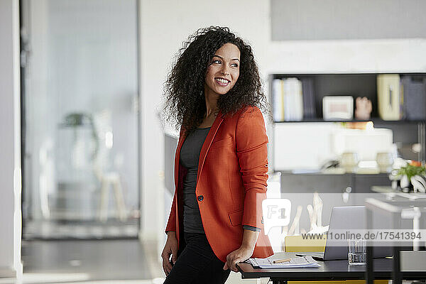 Lächelnde Geschäftsfrau  die am Schreibtisch im Büro träumt