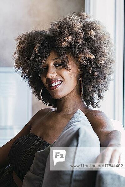 Lächelnde junge Frau mit Afro-Frisur zu Hause