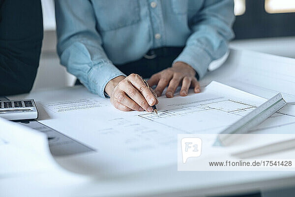 Architekt hält Stift auf Dokument in kleinem Büro