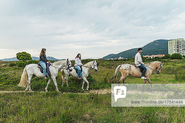 Young friends riding horses on grass