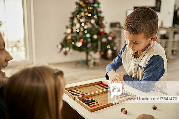 Boy throwing dice playing backgammon at home