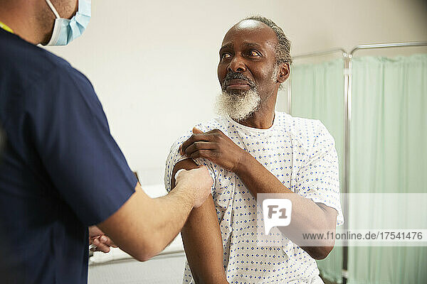 Worried patient looking at nurse disinfecting his arm in medical room