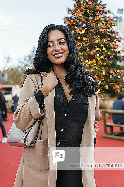 Happy woman wearing overcoat in Christmas market