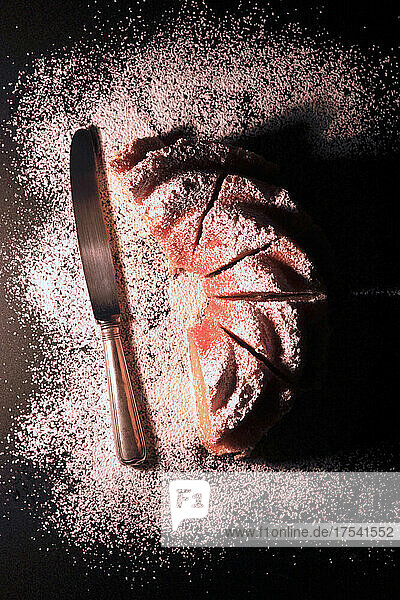 Studio shot of table knife and Kugelhupf cake with powdered sugar