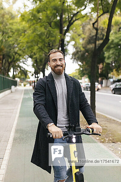 Bearded man with electric push scooter on bicycle lane