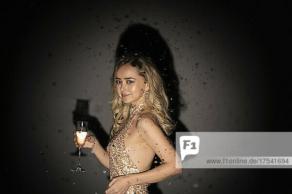 Smiling woman with champagne flute against black background