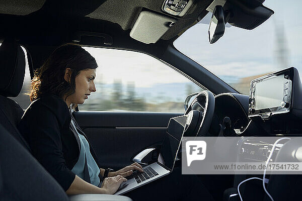 Businesswoman using laptop in driverless car
