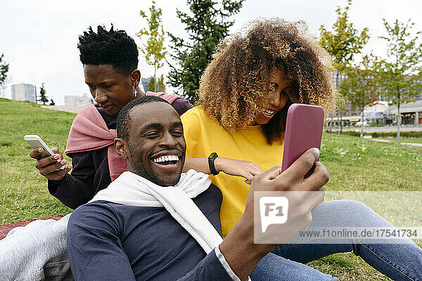 Happy friends using smart phones in park