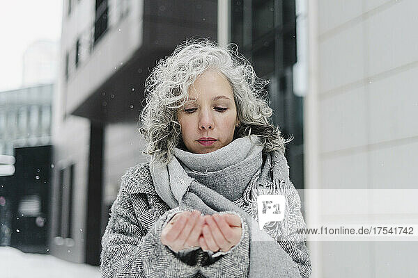 Woman with gray scarf looking at hands in winter