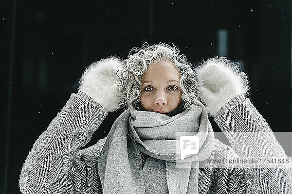 Woman with gray curly hair wearing fur gloves