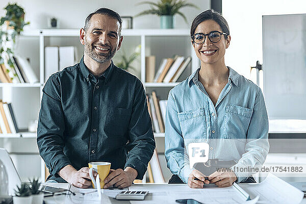 Smiling businessman and businesswoman at desk in small office