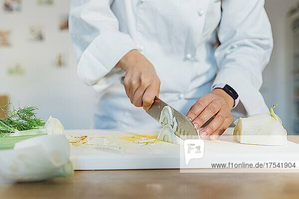 Chef slicing fennel on cutting board at home