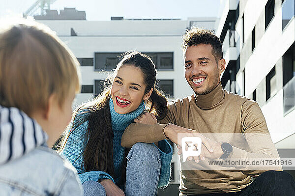Cheerful parents talking with baby boy in city