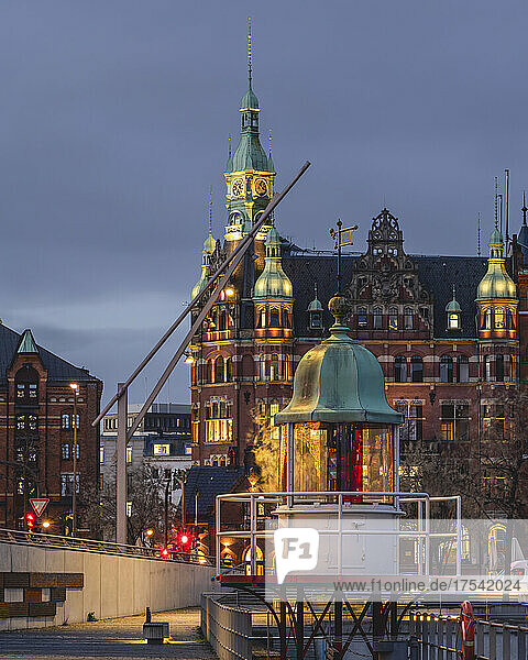 Germany  Hamburg  Speicherstadt district at dusk with lighthouse in foreground and town hall in background