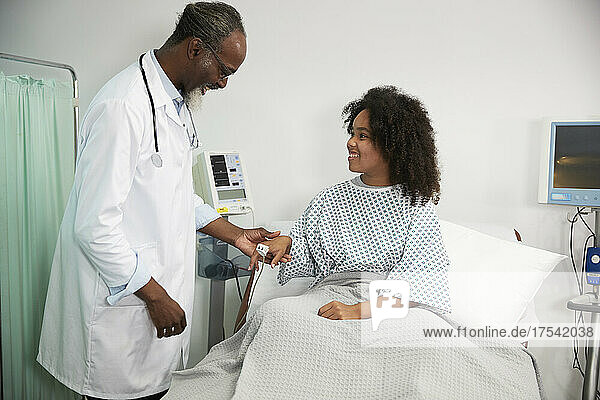 Smiling patient wearing oximeter looking at doctor in hospital