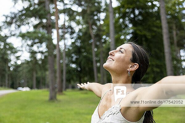 Happy woman with arms outstretched looking up at Cannock Chase
