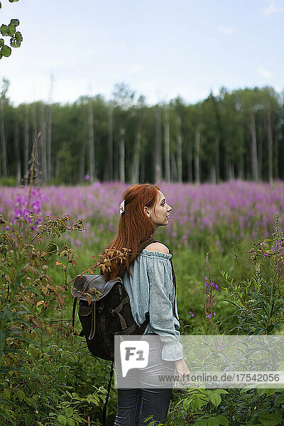 Young woman with backpack exploring in meadow