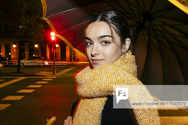 Teenage girl with scarf and umbrella at night