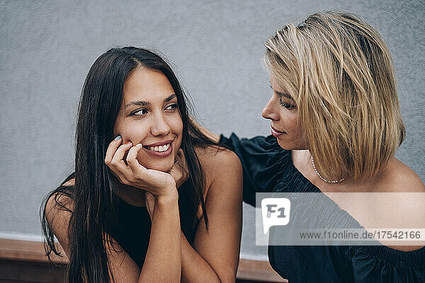 Young woman with hand on chin looking at friend
