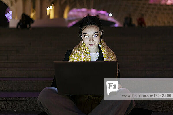 Teenager listening music and using laptop at night