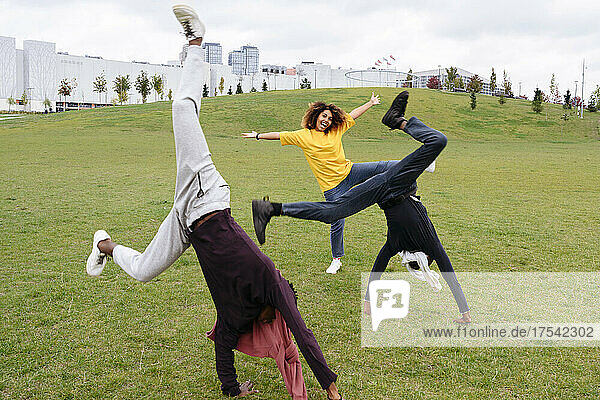 Carefree young men doing cartwheel by friend in park